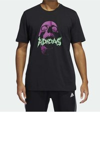 Schwarzes Baumwoll-T-Shirt mit einem grafischen Design eines Schädels in lila und grün, mit lockerer Passform und kurzen Ärmeln.