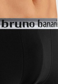 Svarta bomullboxerbriefs med en grå elastisk midja som har texten "bruno banani" i svart. Slät textur med figurnära design.