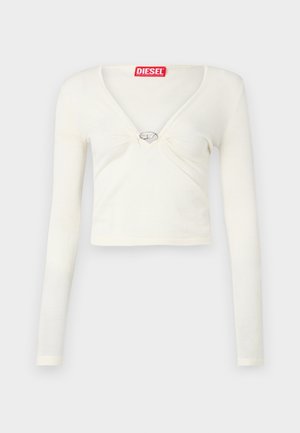 Balts garais piedurkņu crop tops ar V-veida kakla izgriezumu un centrālo metāla akcentu. Mīksta tekstūra ar savelkiem priekšpusē. Zīmola etiķete kakla izgriezumā.