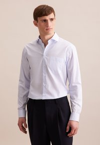 Camicia azzurra chiara con fini strisce bianche, con bottoni sul davanti e taschino singolo sul petto. Maniche lunghe con polsini abbottonati. Tessuto della stoffa liscio.