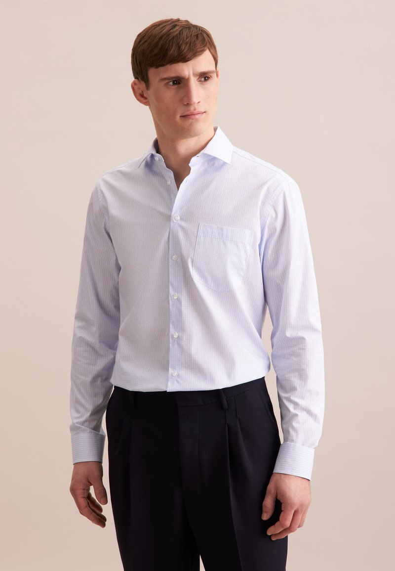 Camicia azzurra chiara con fini strisce bianche, con bottoni sul davanti e taschino singolo sul petto. Maniche lunghe con polsini abbottonati. Tessuto della stoffa liscio.