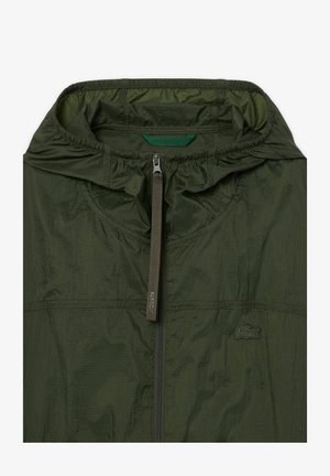 Lichte, donkergroene jas van ripstopmateriaal, met een rits aan de voorkant en een verstelbare capuchon. Inclusief subtiele logo-accent.