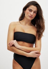 Čierny bikiny set s topom bez ramienok a vysokým pásom. Hladká textúra s minimálnymi švami, vhodná na plavky.