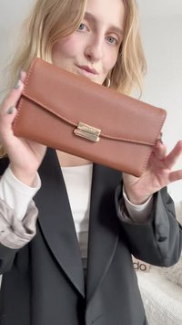 Pruun tekstuuriga nahast rahakott magnetkinnitusega ja õmmeldud äärtega, millel on sujuv disain ja peened kuldedetailid.