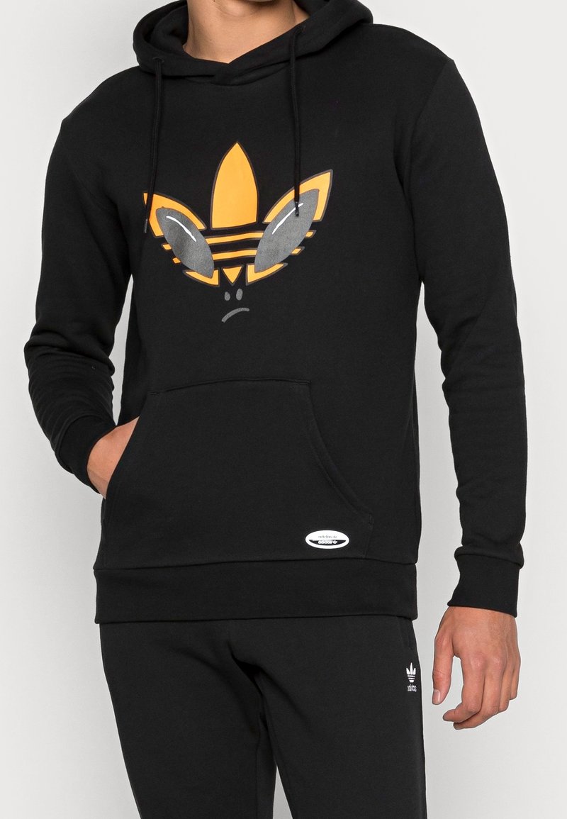 Hoodie noir en coton, arborant un graphique orange vif d'un logo stylisé avec des accents gris. Poche kangourou à l'avant incluse.