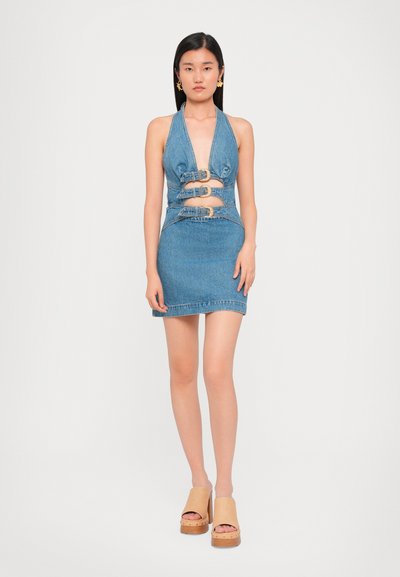 Denim mini dress with halter neck, cut-out detailing, and multiple buckle accents. Features a fitted silhouette and raw hem.