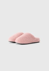 Et par myke rosa fleece tøfler med svarte gummisåler på hvit bakgrunn, skrått forfra.