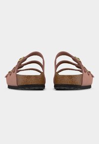 Ζευγάρι ροζ σανδάλια με φελλό πέλμα, τρεις λουράκια με αγκράφες και μαύρες υφασμάτινες σόλες που φαίνονται από πίσω, σε λευκό φόντο.