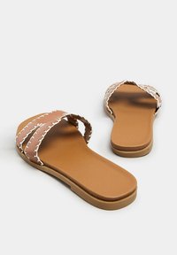 Brązowe klapki z dwoma szerokimi paskami z białym przeszyciem. Płaska podeszwa o gładkiej teksturze. Bez obcasa, z otwartym przodem.