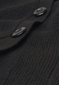 Schwarzer Strickpullover mit strukturiertem Muster, zwei glänzenden schwarzen Knöpfen und einem umgeschlagenen Kragen-Design.