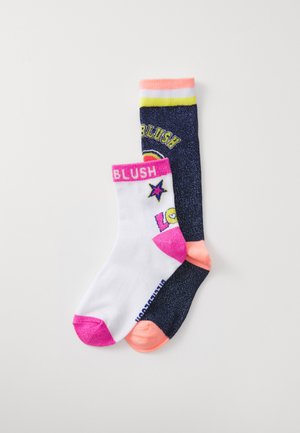 Chaussettes bleu marine montantes avec des paillettes et des accents jaunes ; chaussettes de cheville blanches avec des détails roses et un graphisme d'étoile. Les deux étiquetées "BLUSH."