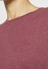 Maglietta di cotone color marrone scuro con una texture liscia, design a girocollo e un sottile motivo mélange, con focus sull'area del collo e delle spalle.