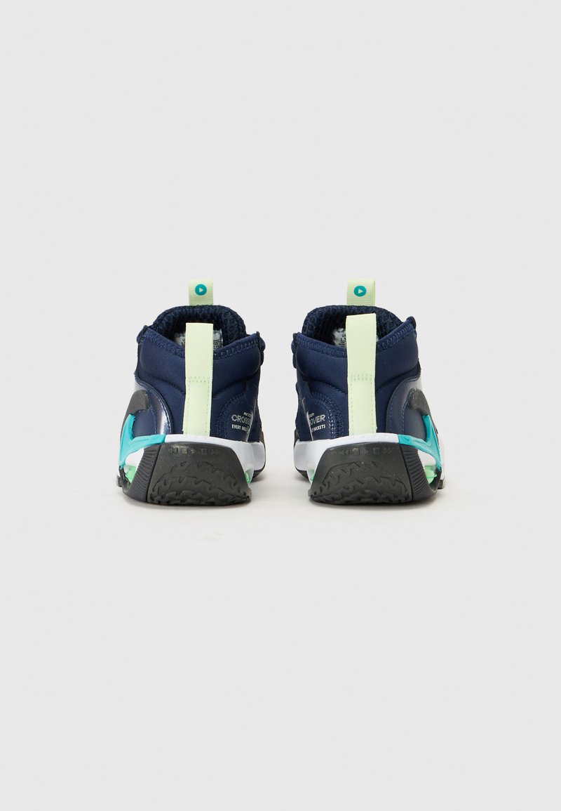 Zapatillas deportivas azul marino con una superficie texturizada, lengüetas en el talón de color verde claro y acentos turquesa en los lados y la suela.