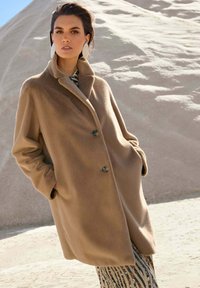 Beige wollen jas met een ontspannen pasvorm, grote kraag en twee knopen. Bevat zijzakken en een zachte, gemarmerde oppervlakte.