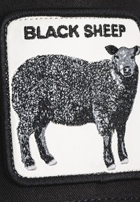 Black patch featuring a black sheep embroidered with textured fur detail, bordered by a white frame and black text reading "BLACK SHEEP."