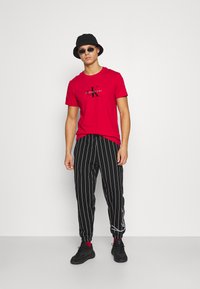 Karl Kani SIGNATURE PINSTRIPE PANTS UNISEX - Treniņtērpa apakšdaļas - black