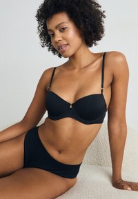 Black lingerie set consisting of a smooth, padded bra with adjustable straps and a matching high-waisted brief, both made of soft, stretchy fabric.