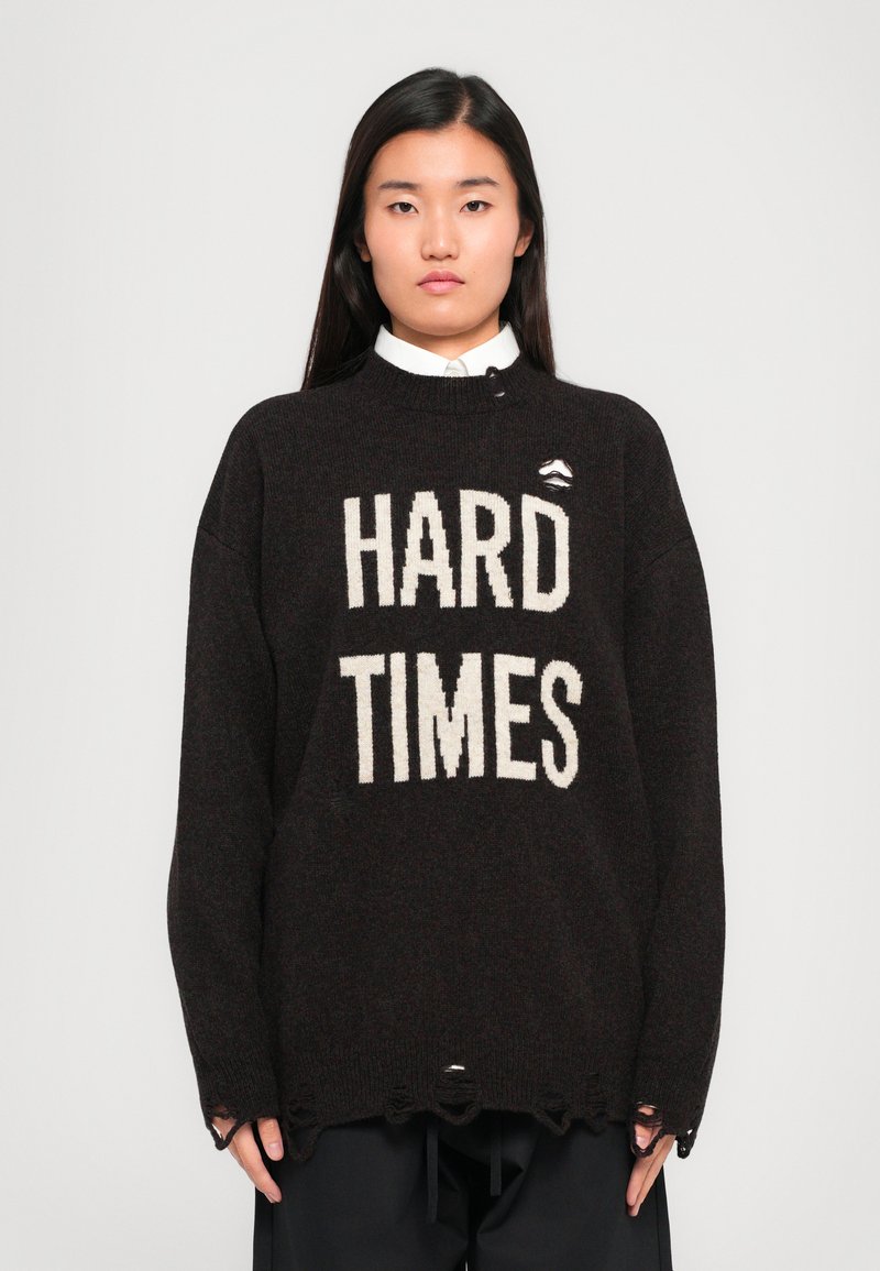 Dark brown oversized sweater featuring white bold text "HARD TIMES," with a round neck, loose fit, and frayed bottom edges.