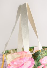 Lærredstaske med blomsterprint i nuancer af pink og grøn, med to teksturerede cremefarvede stropper og åben top.