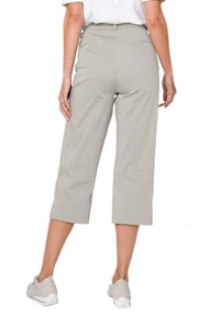 Pantalons croppés gris clair avec une texture lisse, dotés d'une taille ajustée et de deux poches arrière, associés à des baskets grises.