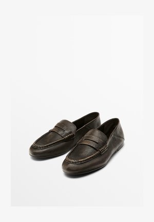 Mocassins en cuir marron foncé avec une texture lisse, des coutures décoratives et une sangle décorative sur le devant. Design à profil bas.