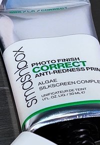 Tube de base correcteur Smashbox, argent métallique avec des accents blancs et verts, affichant le texte "Photo Finish Correct Anti-Redness", 30 ml.