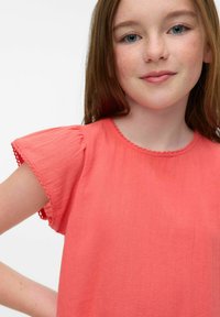 Top corto a maniche corte color corallo con spalle arricciate e scollatura cucita. Tessuto morbido e strutturato con una vestibilità rilassata.