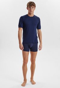 Marineblå kortærmet t-shirt med rund halsudskæring, parret med matchende tætsiddende boxershorts. Materialet ser blødt ud med en glat tekstur.