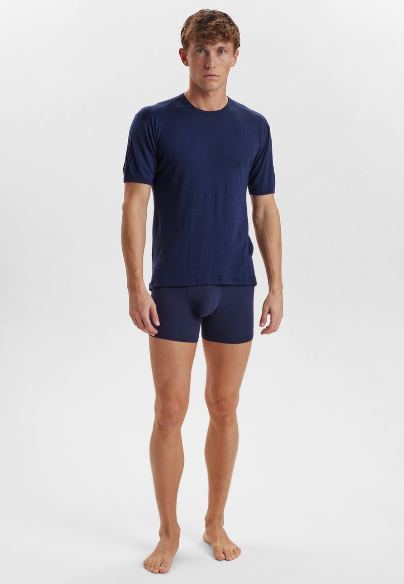 Marineblå kortærmet t-shirt med rund halsudskæring, parret med matchende tætsiddende boxershorts. Materialet ser blødt ud med en glat tekstur.