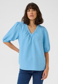 Light blue, textured blouse with short, puffed sleeves and a V-neck. The fabric has a subtle crinkled pattern, offering a relaxed fit.