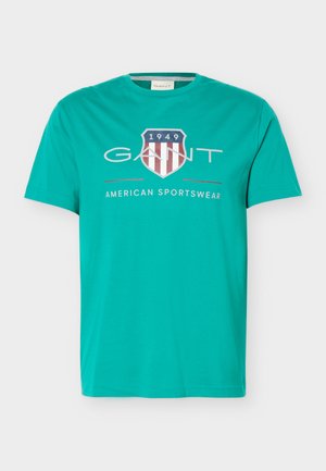 Tricou turcoaz cu mâneci scurte și guler rotund, cu logo GANT, emblema scut, textul "1949" și "American Sportswear" pe partea din față.