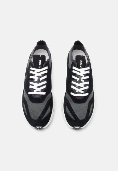 Ζευγάρι μαύρα και γκρι αθλητικά παπούτσια Polo με λευκά κορδόνια και λευκές σόλες, απεικονισμένα από επάνω σε ανοιχτό φόντο.