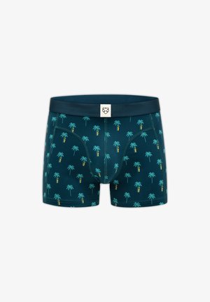 Tumedasrohelised meeste bokserid korduva türkiissiniste palmipuu mustriga ja tumeda vöökohaga, millel on väike valge silt lõvilõuaga logoga.