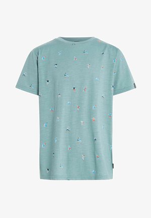 Enfant portant un t-shirt vert avec un petit motif, un short en denim gris, des chaussettes blanches et des baskets montantes noires, se tenant devant un fond blanc.