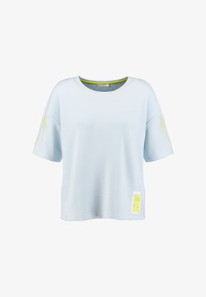 Camisa azul claro de manga corta con cuello redondo, detalles amarillos en las mangas y una pequeña etiqueta amarilla con la frase "JUST BE NICE" cerca del dobladillo.