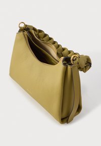 Oliiviroheline nahast käekott tikitud sangaga, kuldse tõmbluku ja kuldsete rõngastega valgel taustal.