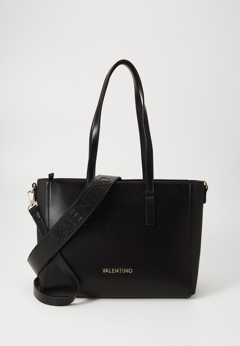 Črna usnjena torba na roke z dvema ročajema in snemljivim ramenskim trakom. Opremljena z izbočenim logotipom "VALENTINO" in zlatimi detajli. Pravokotna oblika.