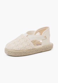 Béžové espadrilky s tkaným texturovaným materiálem, elastickými křížovými popruhy a jute podešví. Uzavřená špička a otevřená pata.