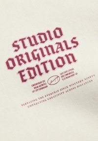 Krémová tkanina s bordovou vyšívanou textáciou: "STUDIO ORIGINALS EDITION" nad ďalšími detailmi v modernom písmovom štýle.