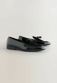 Schwarze Lackleder-Mokassins mit einem Oberteil aus Wildleder und Quastenverzierung. Elegantes Design mit niedrigem Absatz und glatter Oberfläche.