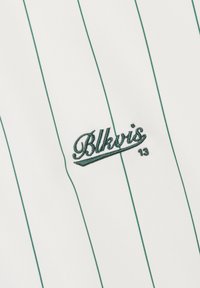 Biały materiał z pionowymi zielonymi cienkimi prążkami i zielonym haftowanym logo "Blkvis 13" na środku.