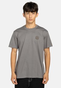 Grijze crew neck t-shirt van zachte stof, met een klein bruin logo op de borst, en korte mouwen met een ontspannen pasvorm.