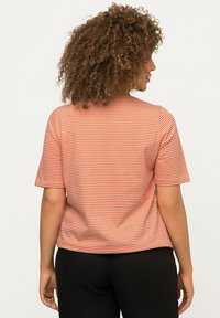 Camiseta de rayas en algodón naranja y blanco, de manga corta, con cuello redondo, de corte relajado y dobladillo recto. Sin adornos notables.