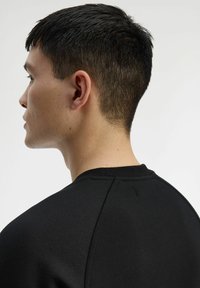 Felpa nera a girocollo con una superficie testurizzata. Presenta maniche raglan e dettagli di cucitura discreti nella zona del collo e delle spalle.