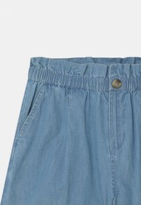 Pantalones cortos azul claro con una cintura elástica, cierre de botón, dos bolsillos laterales y una textura de tela suave y lisa.