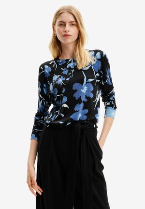 Maglione nero con stampa floreale blu, maniche lunghe, scollatura e polsini a costine, abbinato a pantaloni neri a vita alta con cintura in vita.