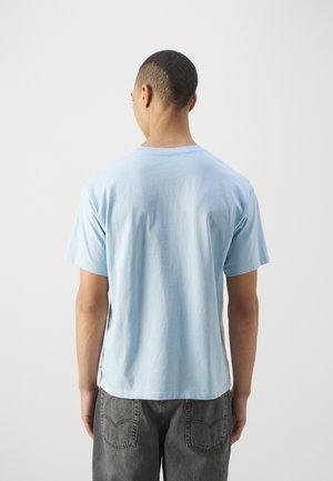 T-shirt en coton bleu clair avec un col rond et des manches courtes, présentant une coupe décontractée et une texture lisse, affichée de dos.