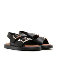 Black leather sandals featuring a flat sole, two buckle accents, open toe and heel design, with a smooth texture and brown insole.
