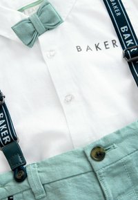 White cotton button-up shirt with a blue-green bow tie and blue suspenders featuring "BAKER" in white, paired with light green fabric pants.