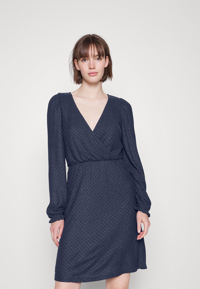 Vestido envolvente azul-marinho com mangas longas, decote em V, tecido texturizado, cintura ajustada e bainha até ao joelho. Apresenta detalhes de mangas franzidas.